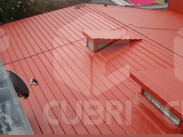 A freshly painted red metal roof with two small windows and a satellite dish.