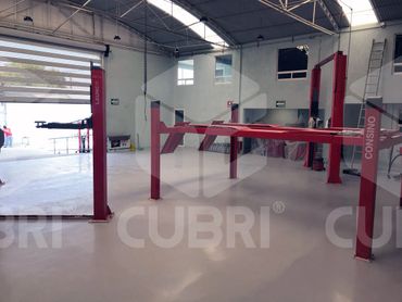 Empty car lift bays inside a clean, well-lit auto repair shop.