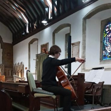 Person playing cello in a church.