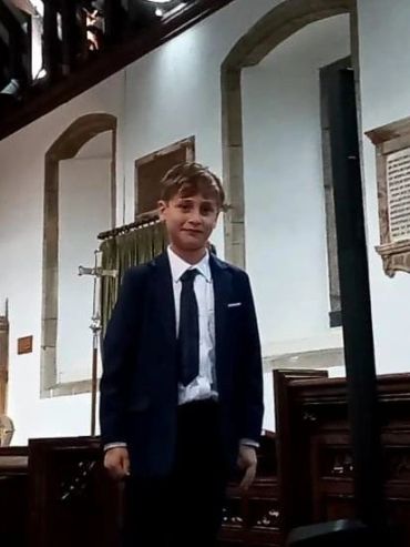 Young boy in a suit standing inside a church.