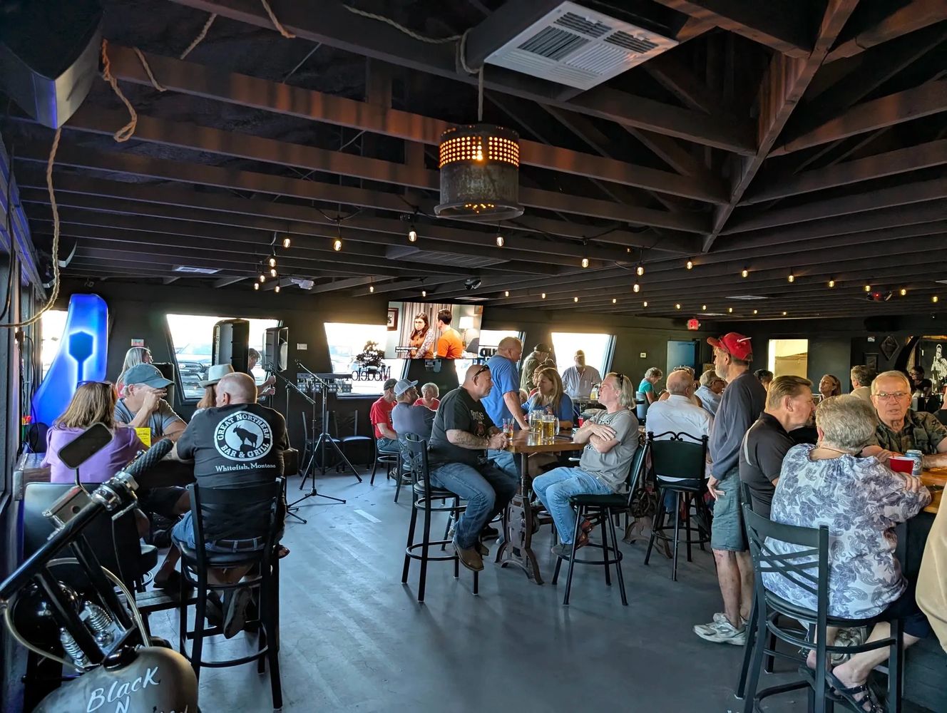 People socializing in a cozy bar with dim lighting and exposed beams.