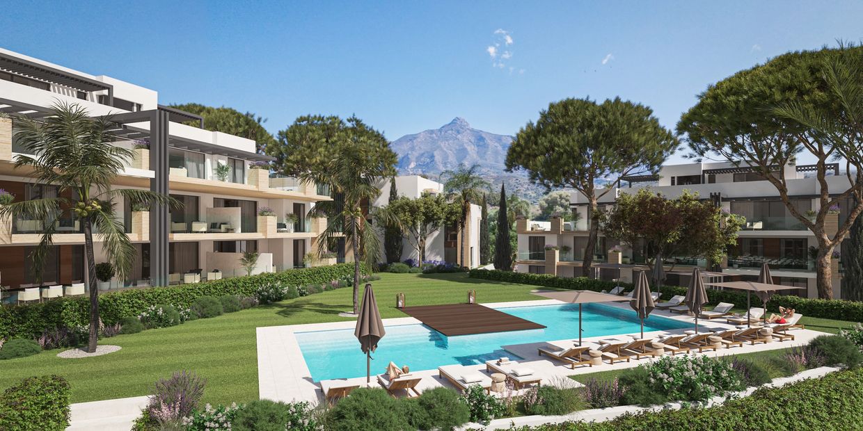 Modern apartment complex with pool and mountain view under clear blue sky.