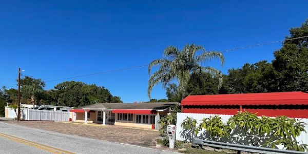 Single-story house with red roof under clear blue sky.