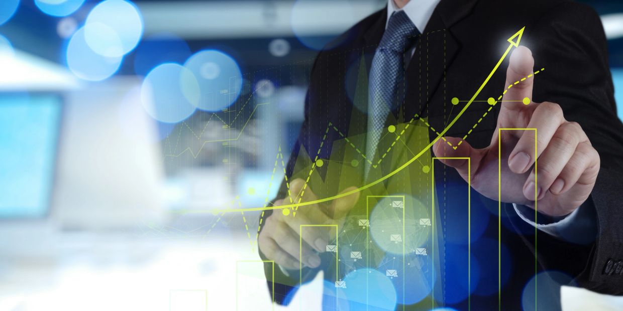 Businessman pointing at rising financial graph.