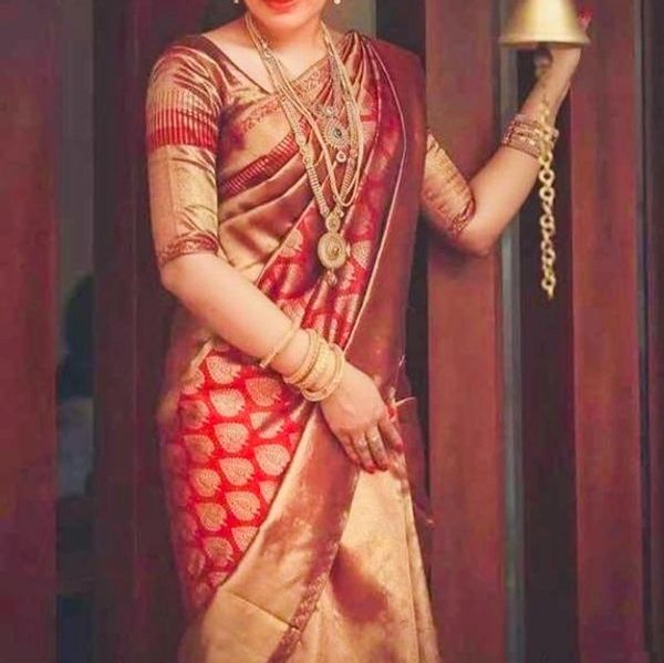 Woman in elegant traditional saree holding a brass bell.