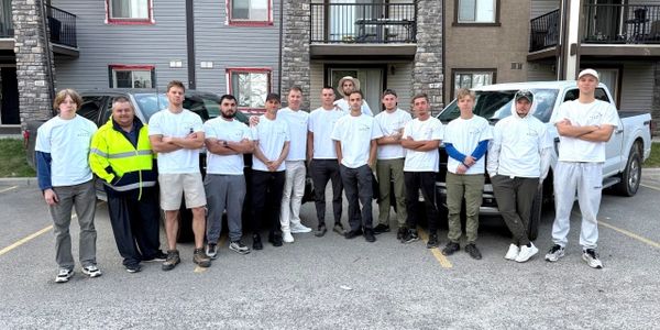 Group of men standing in a parking lot wearing white shirts.