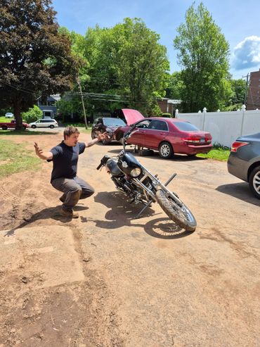 Man reacts to fallen motorcycle on a sunny day.