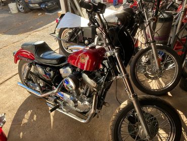 A red Harley-Davidson motorcycle parked in a garage with another bike behind it.