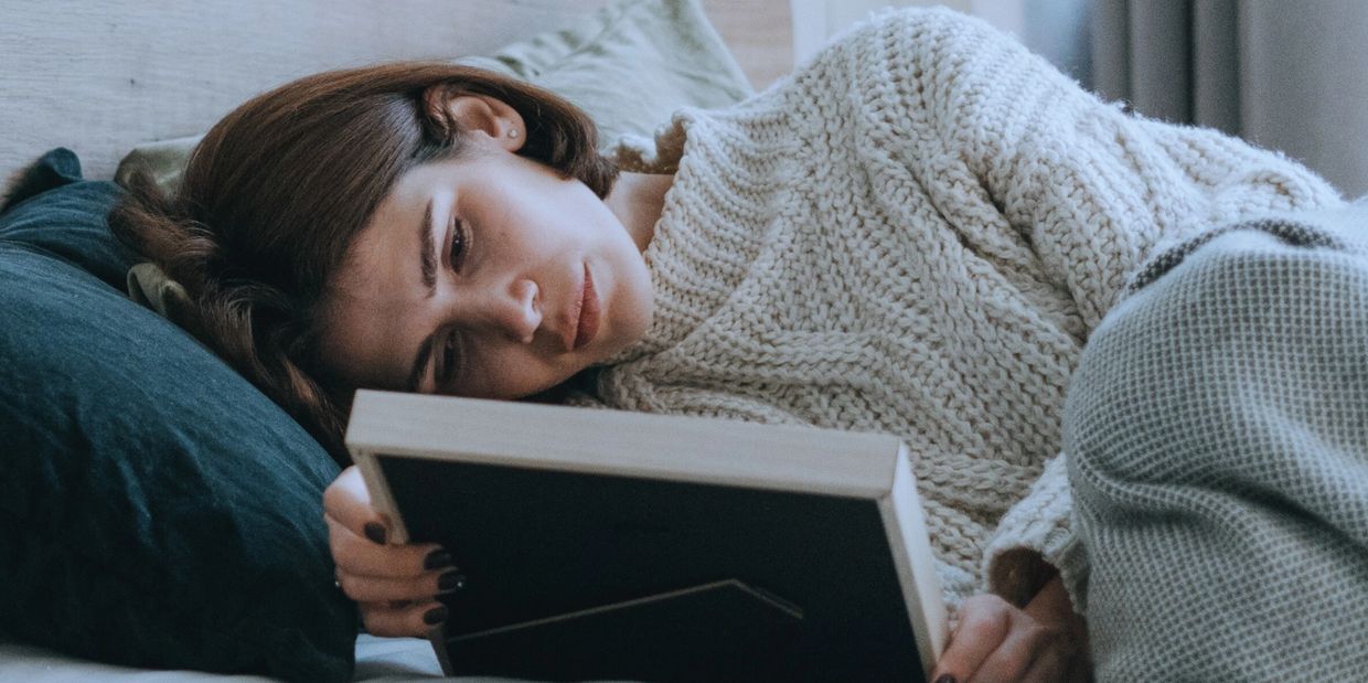 Grieving woman on her bed holding and looking at a picture frame