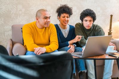 Family browsing laptop together on couch.