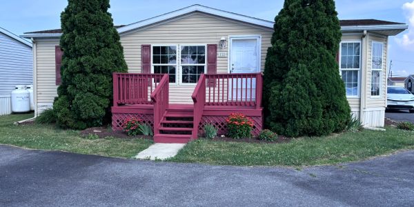 Single-story house with a red porch and two large trees.