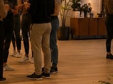 People standing together indoors on wooden floor.