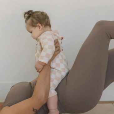Adult lifting baby while exercising on floor.