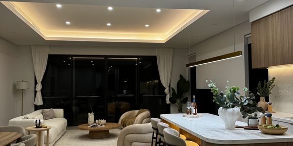 Modern open living room and kitchen with warm lighting and neutral tones.