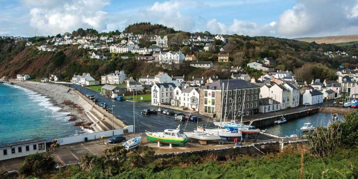 Coastal town with boats and white houses on a hill.