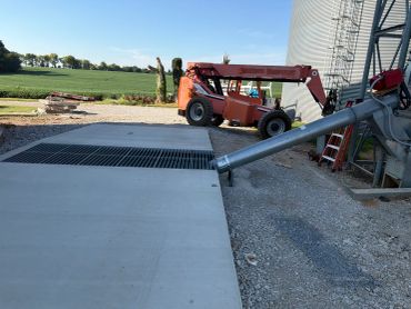 Construction machinery next to a silo with a conveyor pipe.