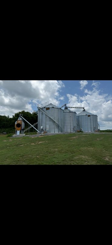 Farm grain silos under a partly cloudy sky.