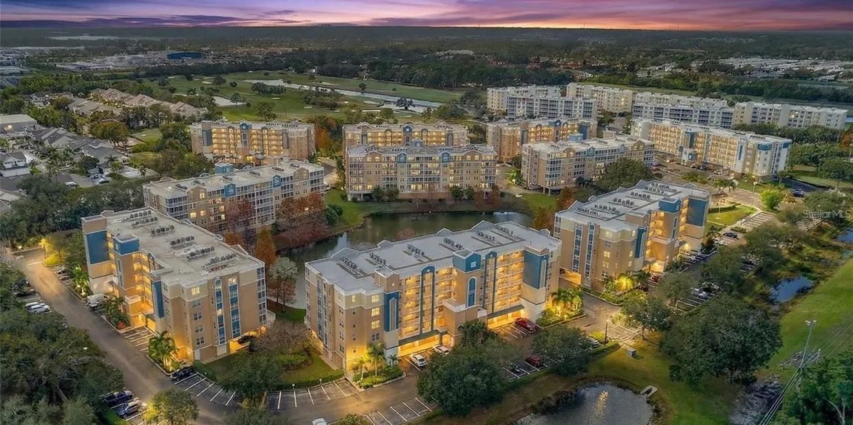 Aerial view of a residential complex with lit buildings at dusk.
