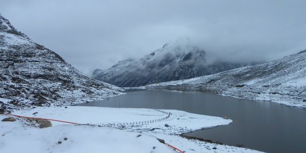 Snow-covered mountains and a lake under a cloudy sky.