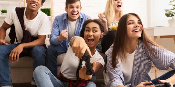 two girls playing video game and others are cheering 