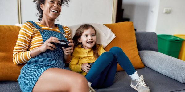 a woman and girl sitting on a couch and playing 