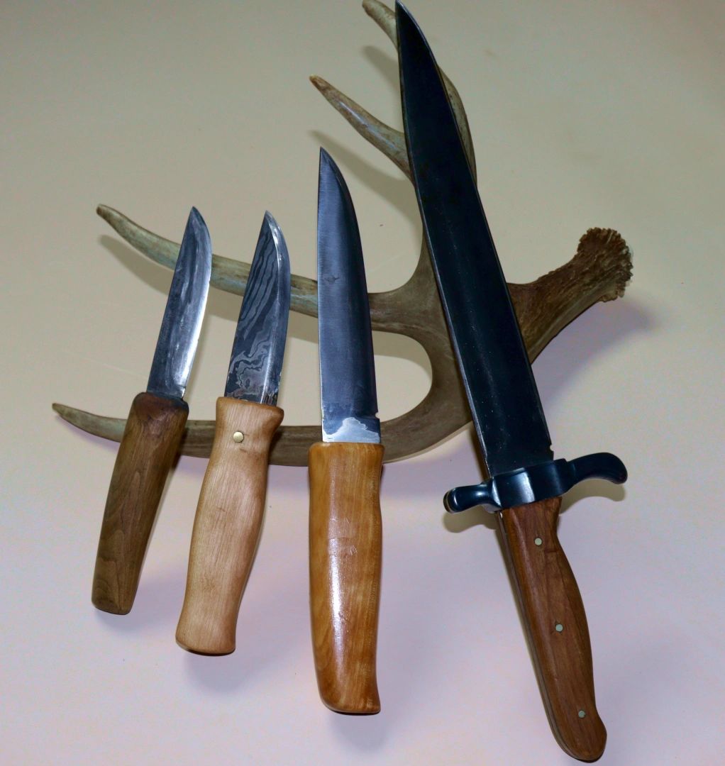 various hunting knives resting on a deer antler