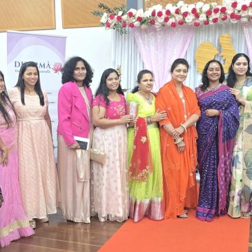 Group of women dressed in colorful traditional and modern attire posing indoors at an event.