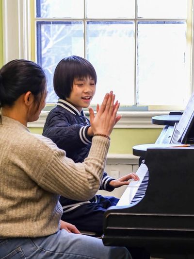 Women giving a high-five to child at a piano lesson 