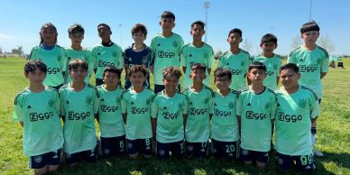 Youth soccer team posing on grass field.