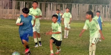 Kids playing soccer on a grassy field during the day.