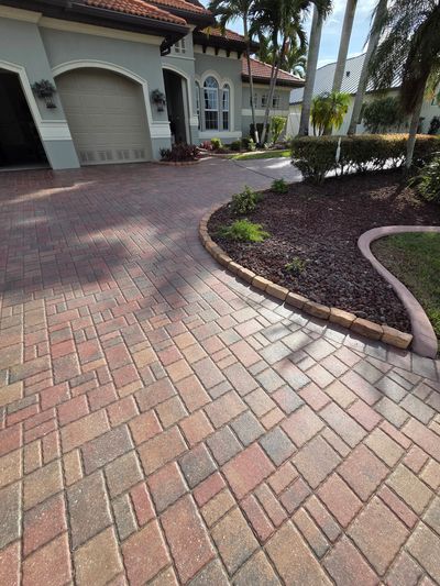 A clean brick driveway leading to a garage of a suburban home.