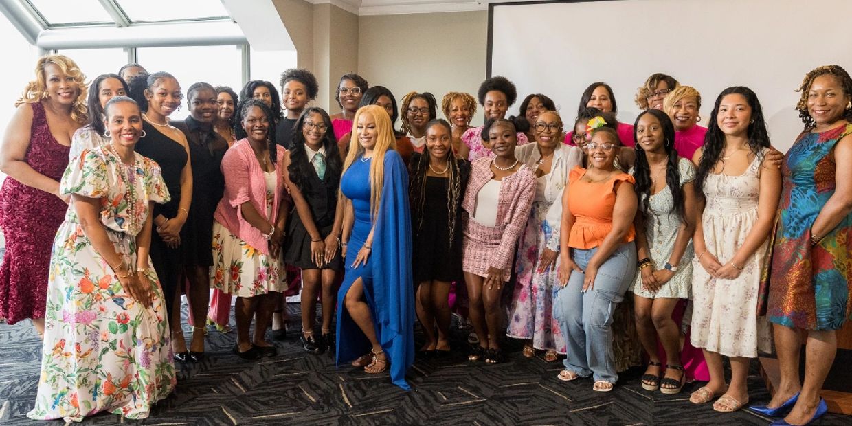A group of diverse women posing together indoors in colorful attire.