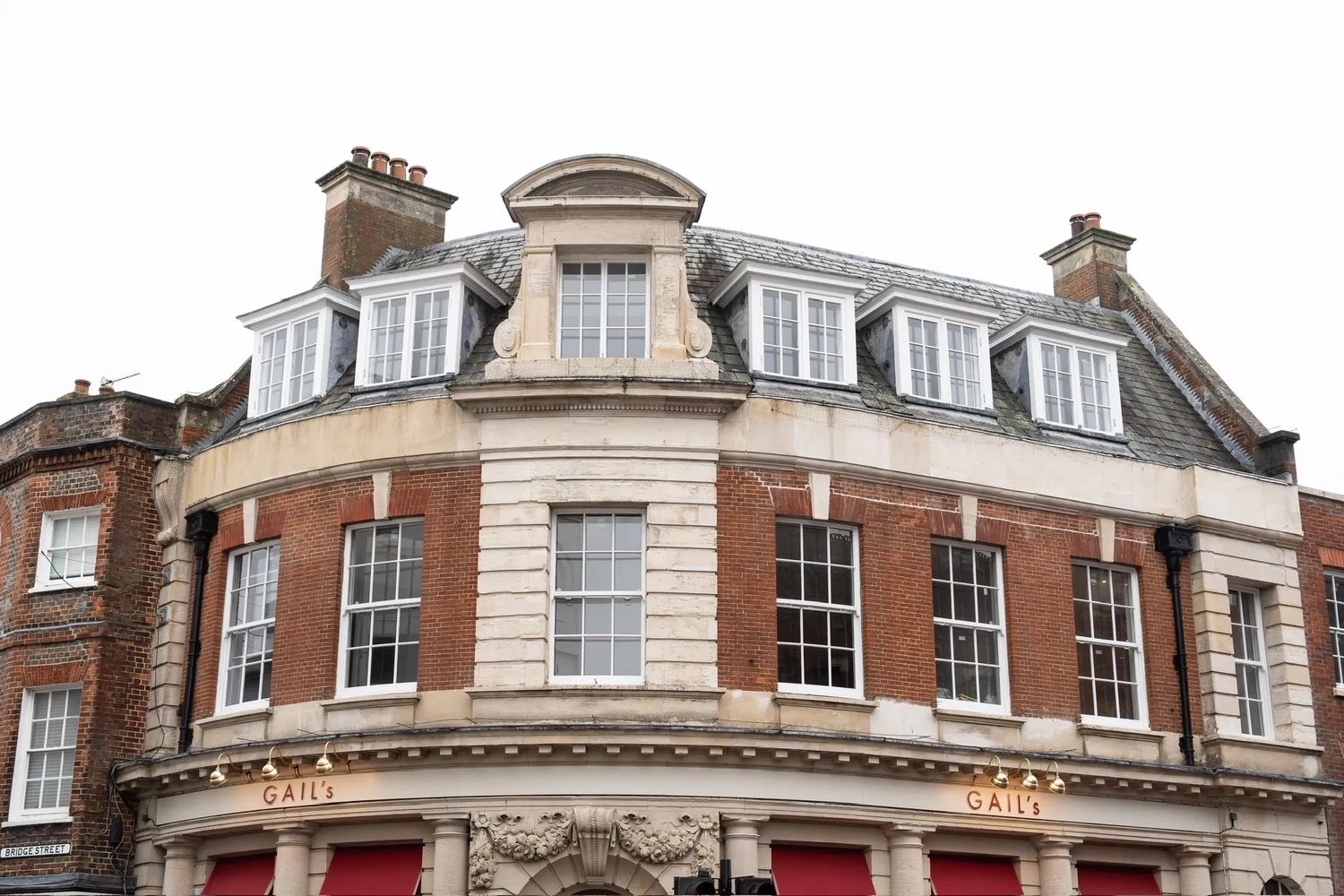 Historic red brick building with white window frames and arched roof windows.