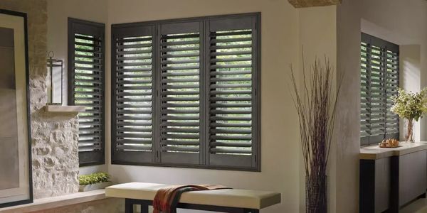Cozy room with stone wall and dark window shutters letting in natural light.