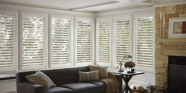 Cozy living room with white plantation shutters and gray couch.