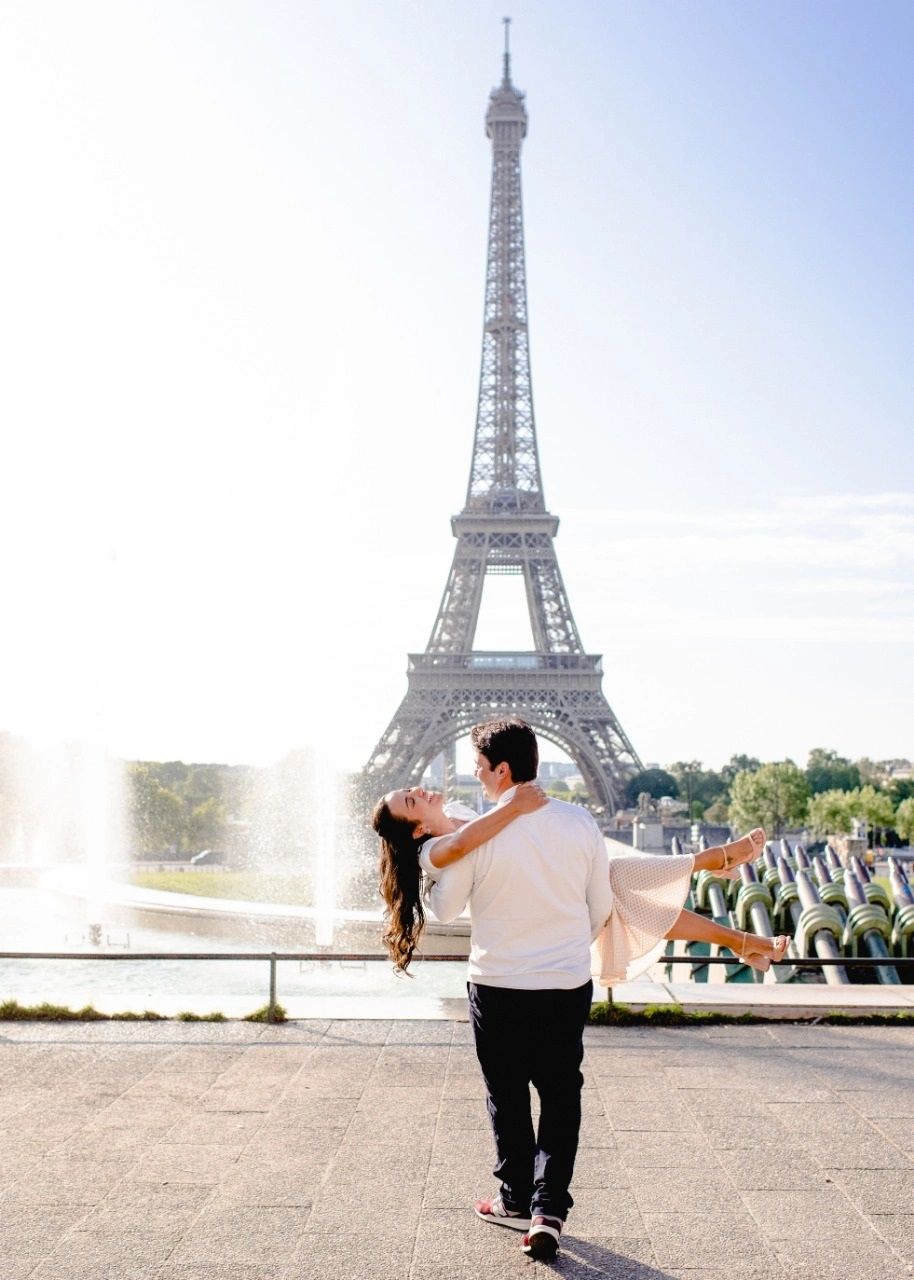 Casal feliz em frente à Torre Eiffel em Paris.