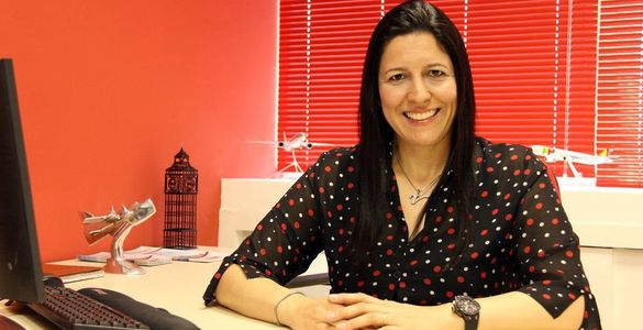 Mulher sorridente sentada à mesa em escritório.