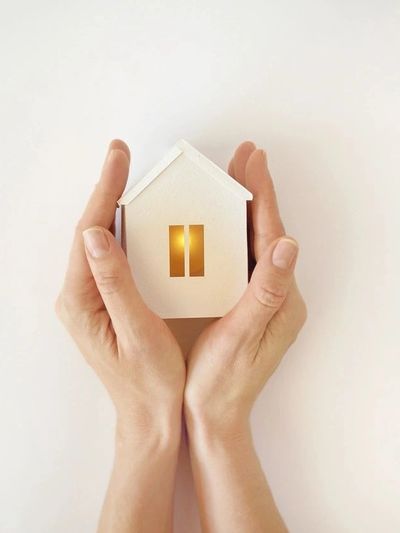 The model of the White House with warm light inside in female hands on a white background