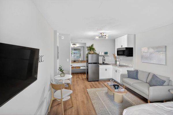 Modern studio apartment with kitchen, seating area, and TV.