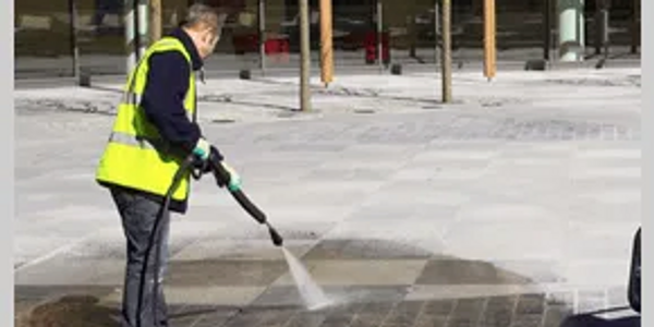 Soft washing a paved are on a commercial site.