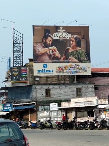 Busy street corner with billboard advertisement and traffic.