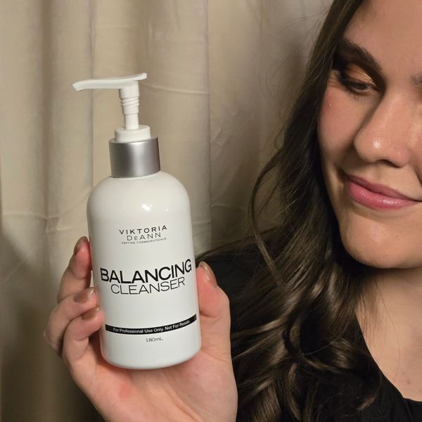 Woman holding Viktoria DeAnn Balancing Cleanser bottle with a smile.