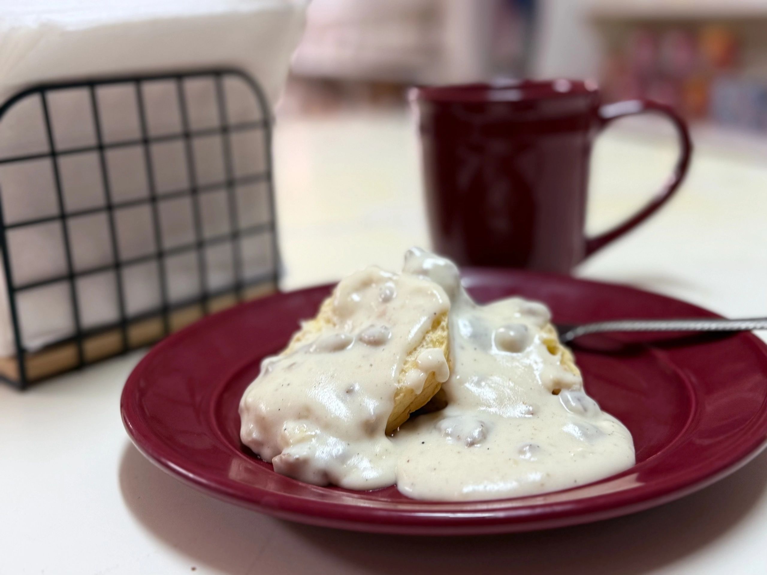 Biscuits with creamy sausage gravy on a red plate.