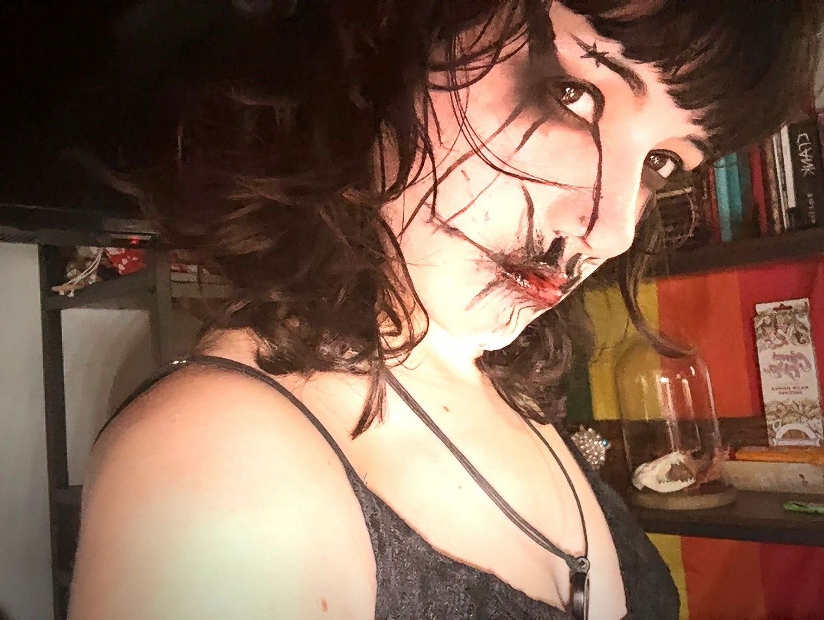 Person with dark makeup and a black star on forehead looking sideways.