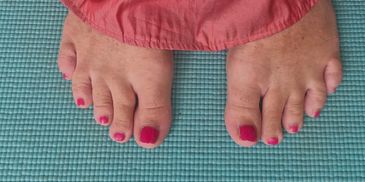 Feet with pink nail polish on a blue mat beside a pink embroidered dress.
