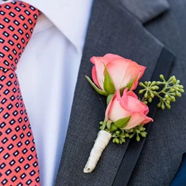 Two pink rose boutonniere on a dark suit.