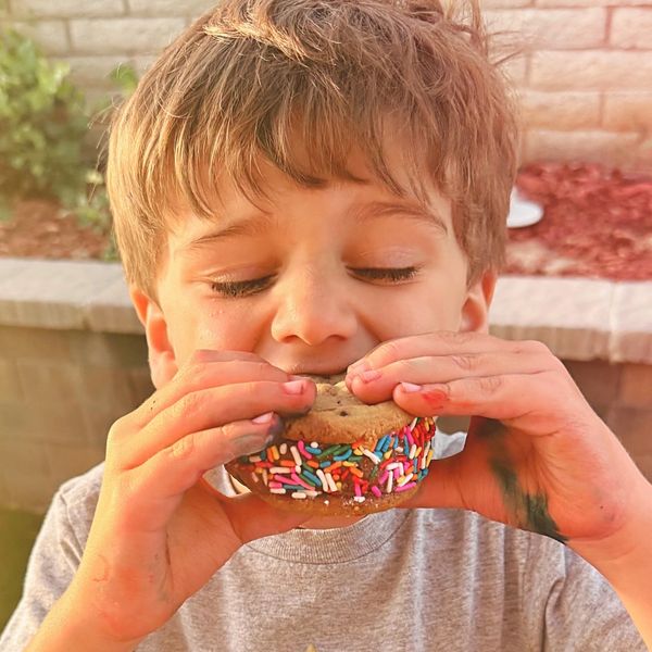 young boy eating a chocolate ice cream sandwich during summer
