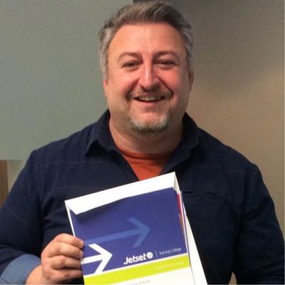 Smiling man holding a Jetset travel brochure.