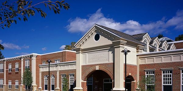 A classic brick school building under a bright blue sky.