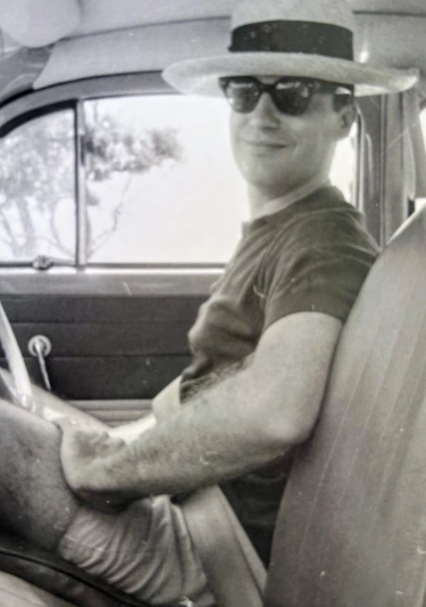 Man in sunglasses and hat sitting inside a car.